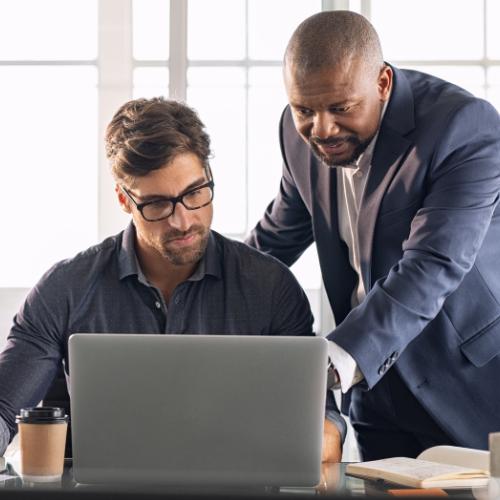 Supervisor assisting employee who is looking at a laptop 