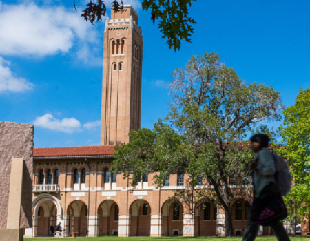 Student walking in front of a building on Rice's campus