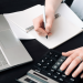 vector file of a person writing and using a calculator with a computer keyboard adjacent