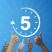 Clock with number five in the middle and hands doing thumbs up